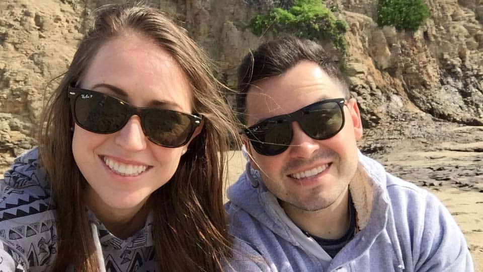 Couple taking a selfie at the beach wearing sunglass with a big smile on their faces