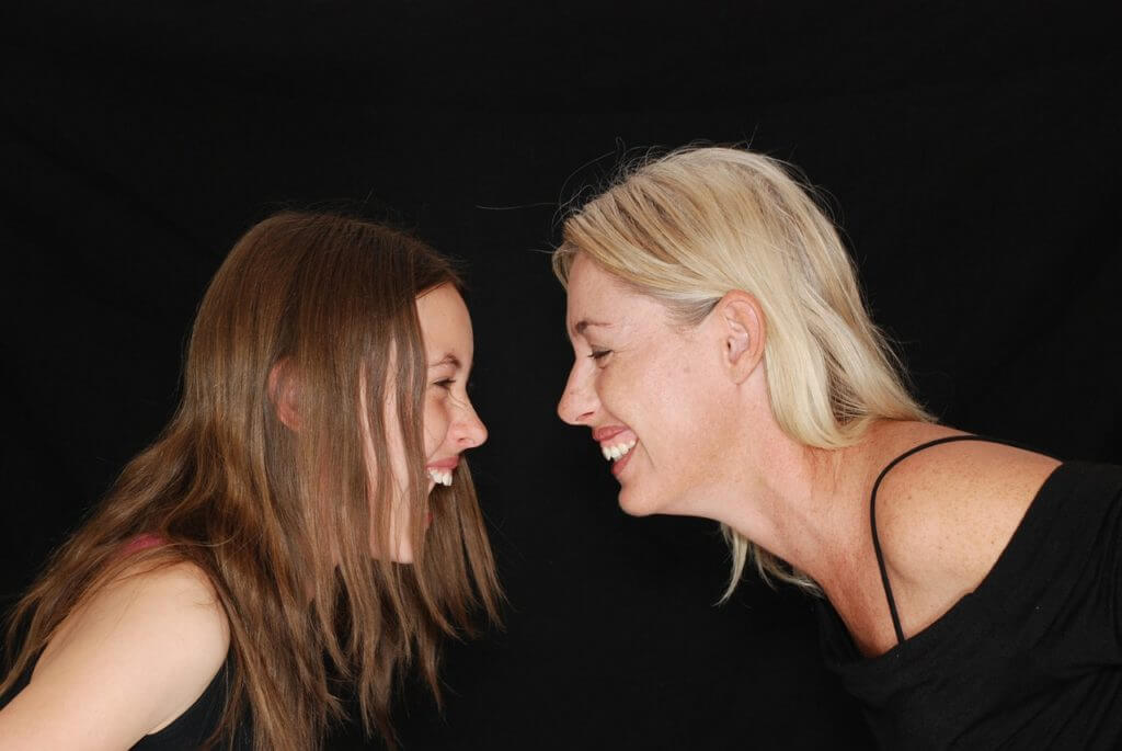 Two women facing each other laughing