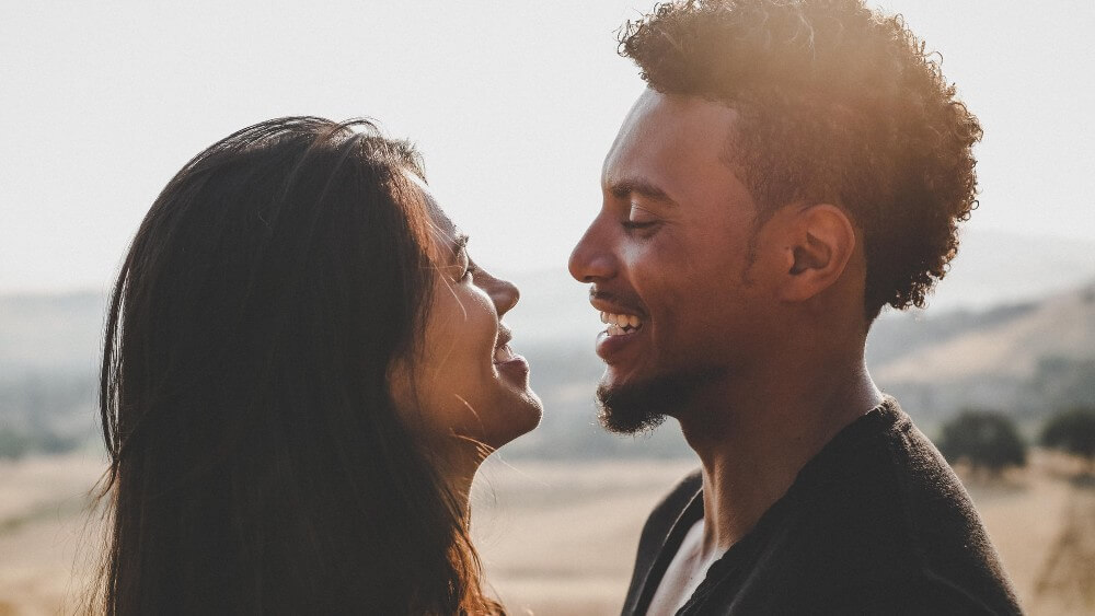 close up photo of black afro man smiling at his girlfriend 