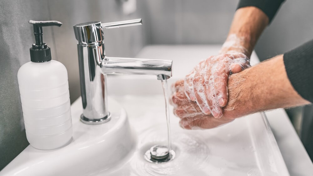 man washing hands in a bathroom basin