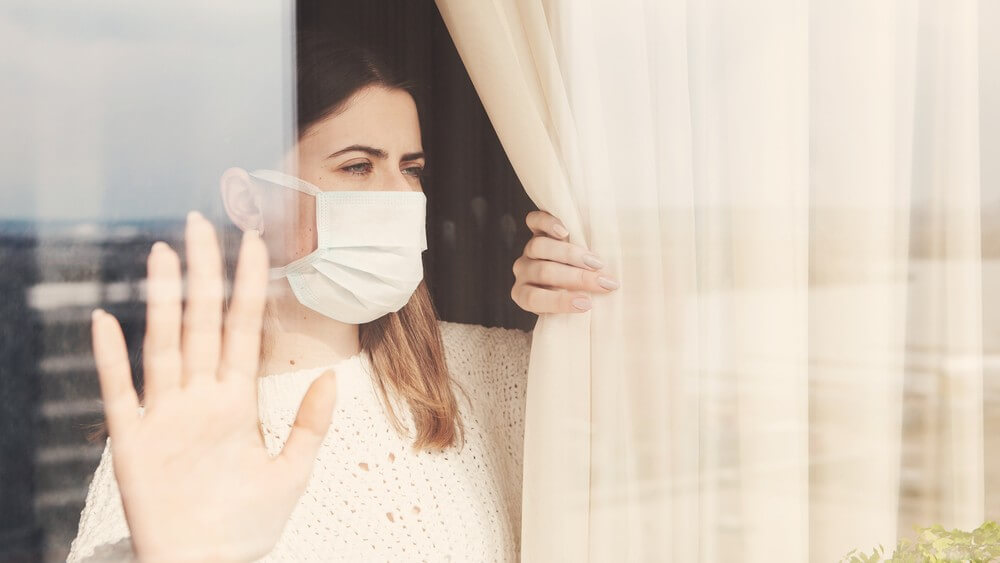 isolated woman wearing white mask and looking through a window