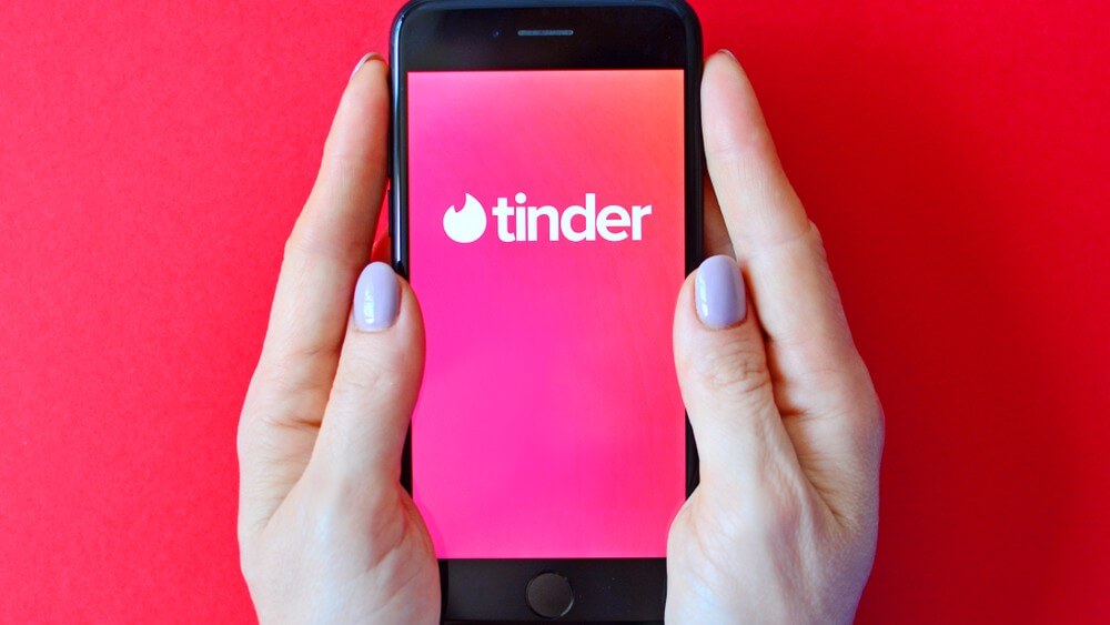 female hand holding a smartphone with Tinder on the screen