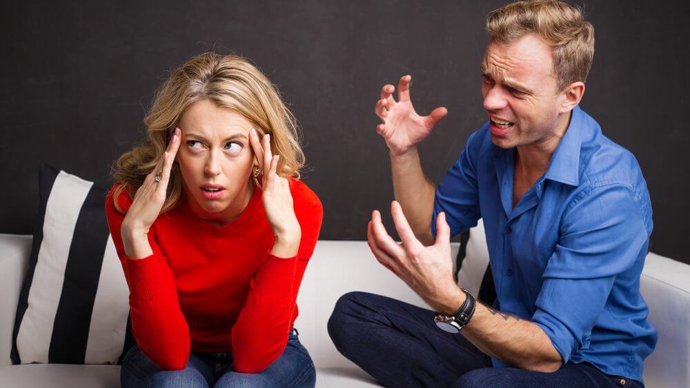 man yelling at his partner on a white sofa