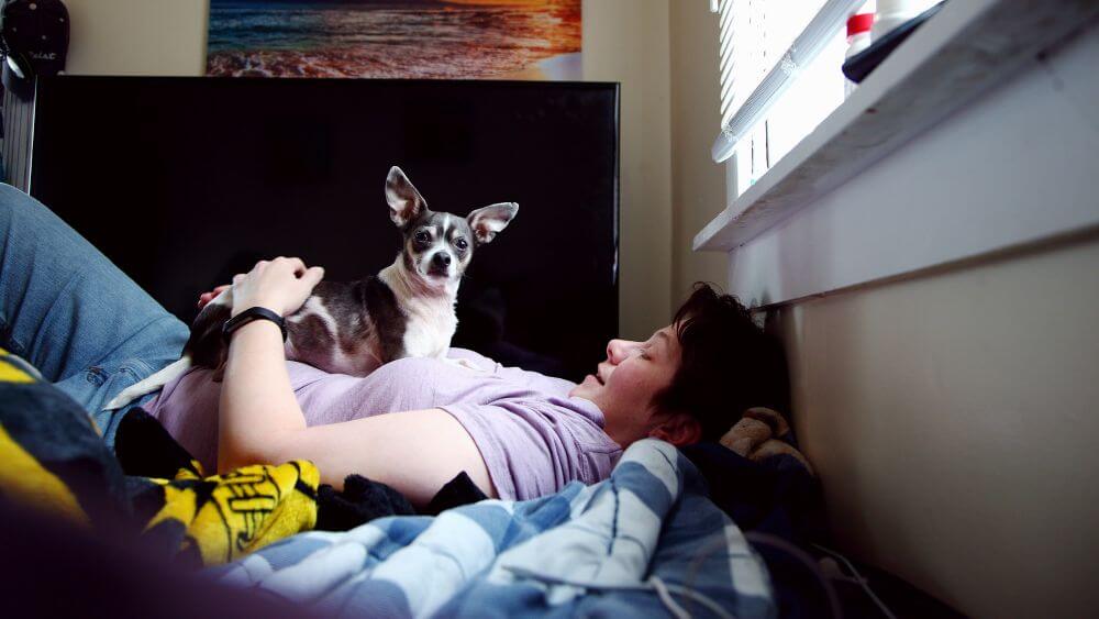 Woman lying in bed holding her dog