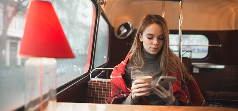 A girl with a cup of coffee sits in a coffee