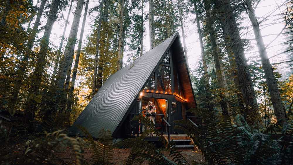 woman standing on the patio of a light up wooden bush house