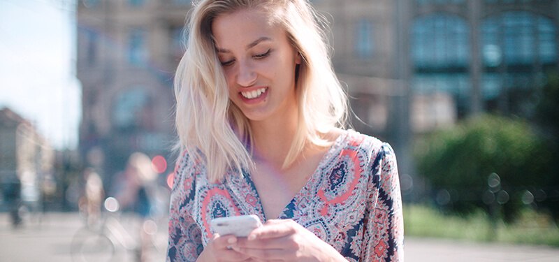 Beautiful young woman typing on phone