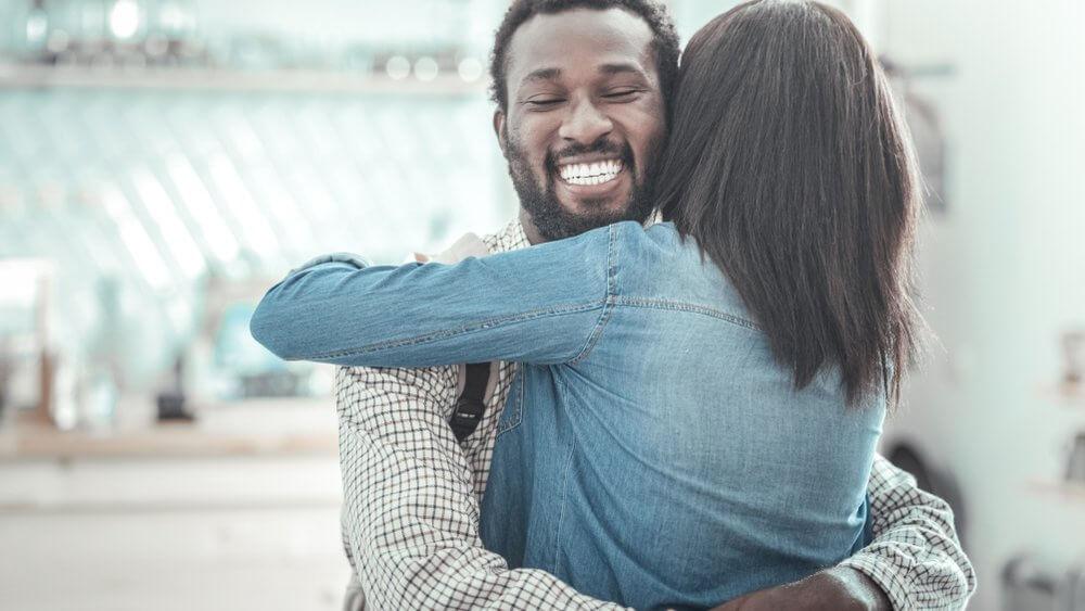 African American man hugging his partner with a big smile