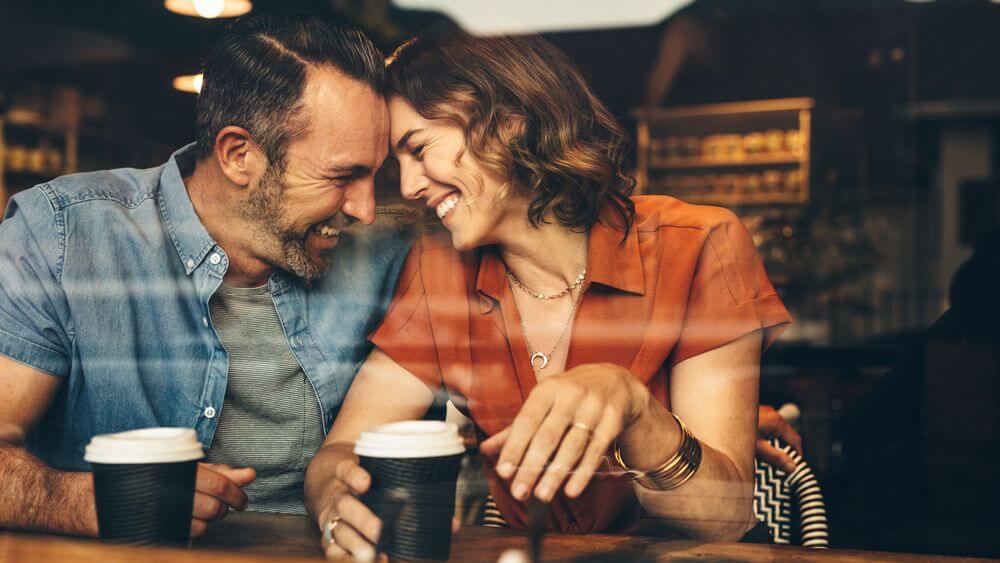 couple giggling over coffee with their foreheads locked together