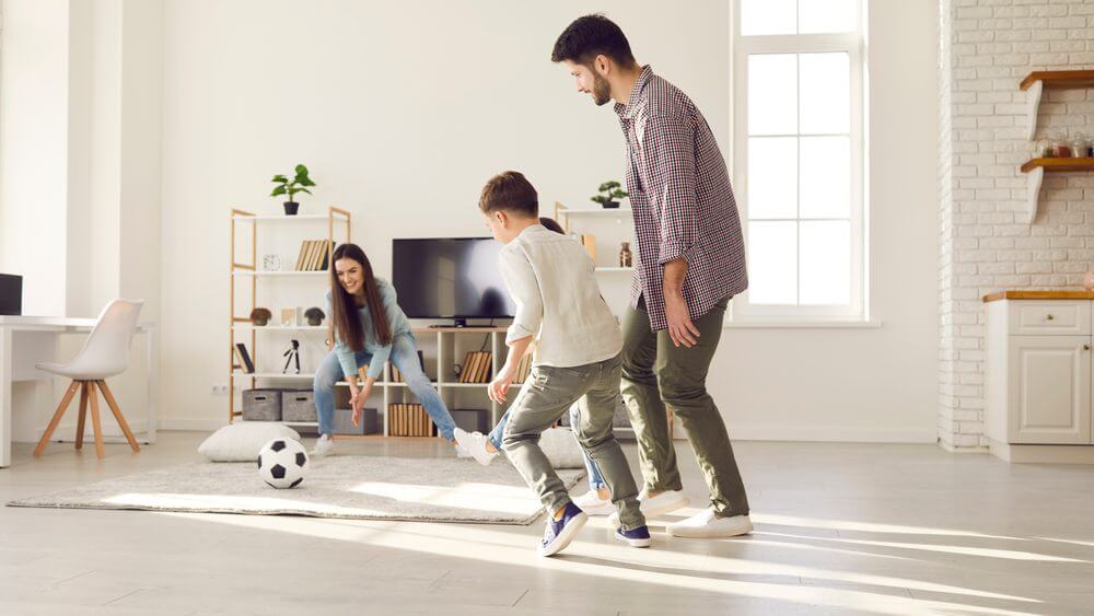 lovely family of three playing soccer in living room