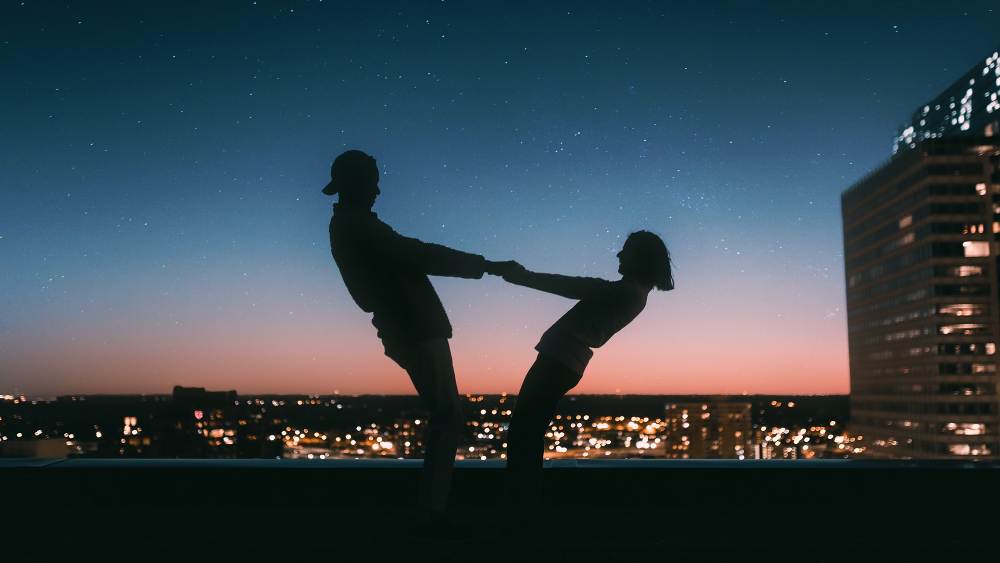 two lovers holding hands in silhouette night background