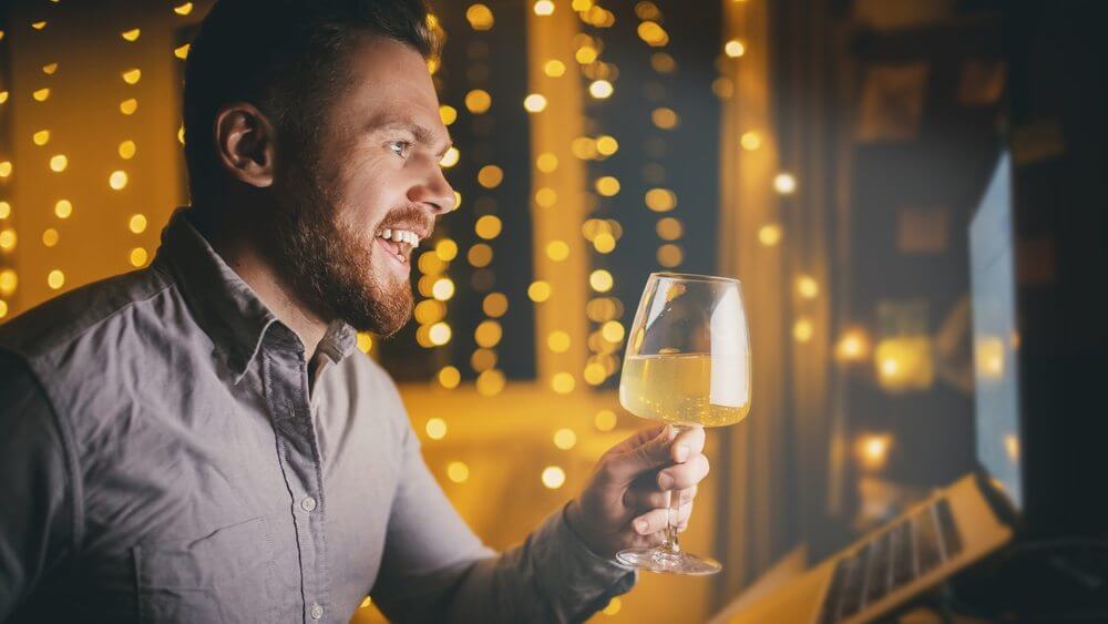 lover man holding up a glass of wine in a video call