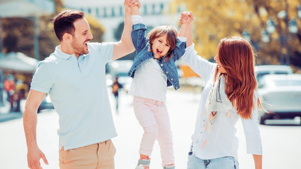 happy family of three having fun together on the street