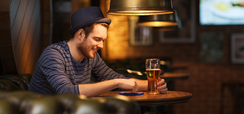 Man with smartphone and beer texting