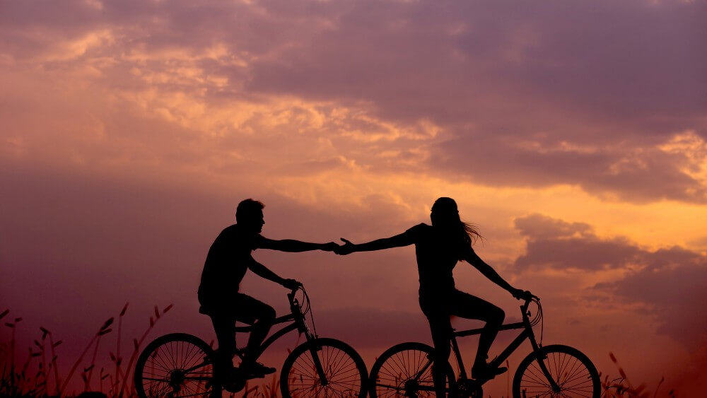 silhouette photo of couple enjoying a bike ride in sunset