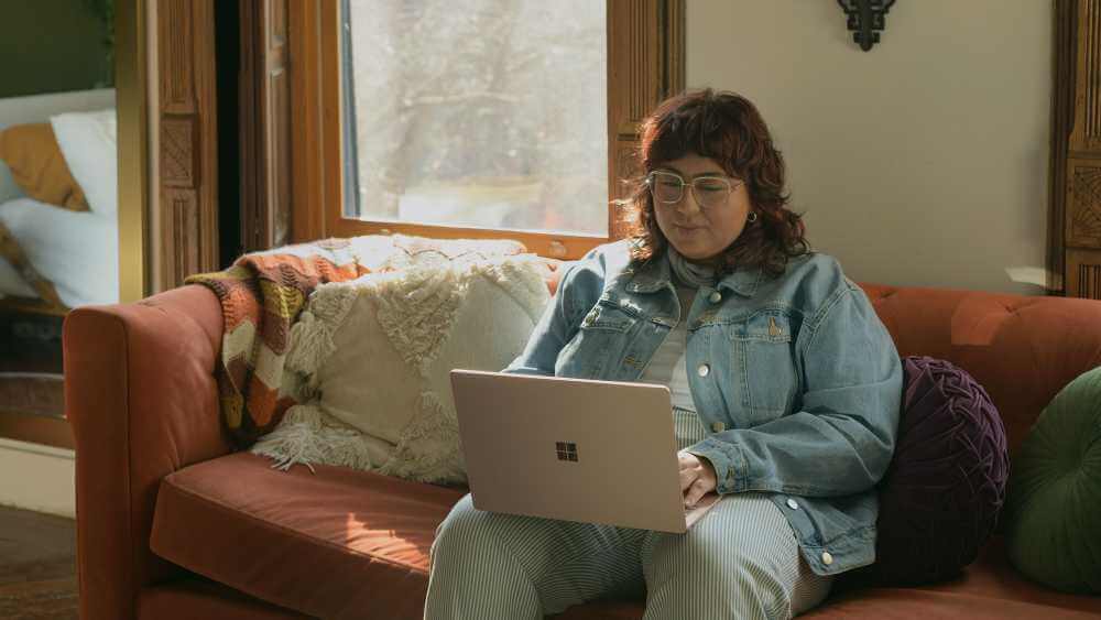 woman wearing a denim shirt having a zoom date on her windows laptop 