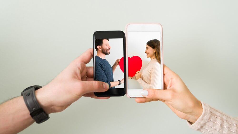 close up photo of a couple bringing their phones together to form a heart symbol