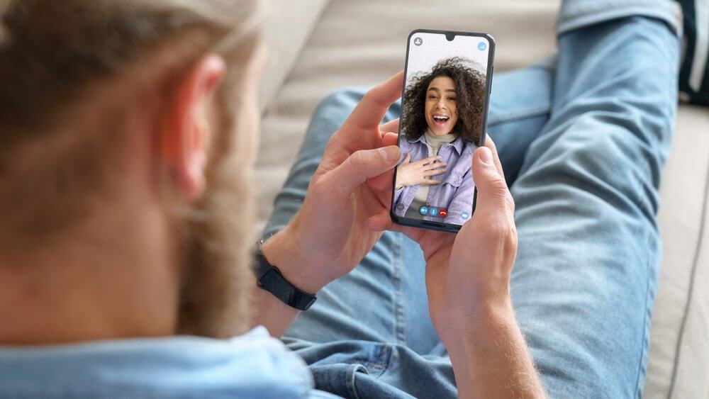 young man wearing blue pants video chatting a Hispanic woman