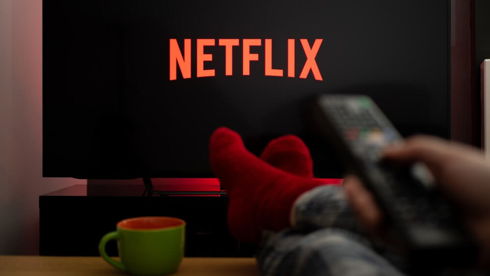 a person wearing red socks using a tv remote for Netflix