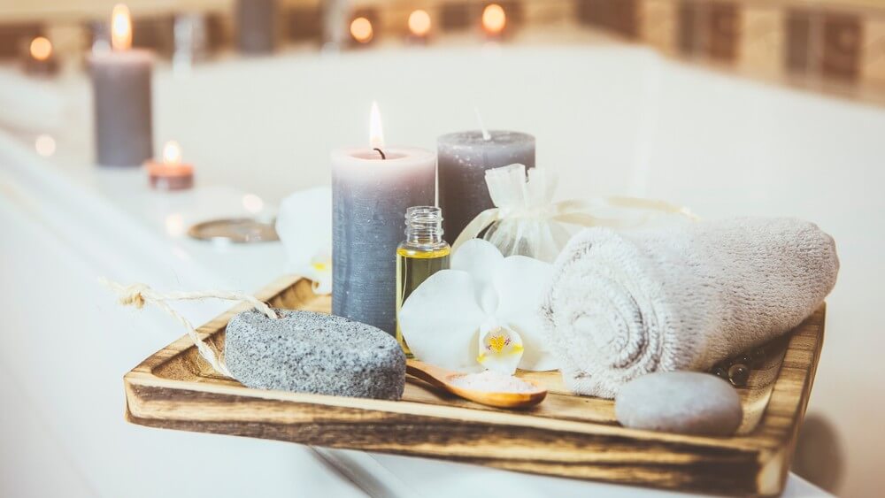 spa towels, candles, hot stone on a wooden tray