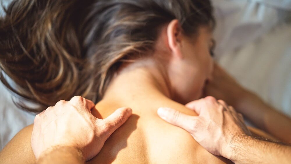 man massaging wife's shoulder in bed