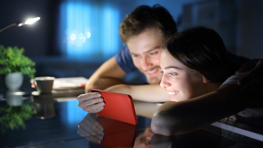 happy couple enjoying a movie on their red smartphone