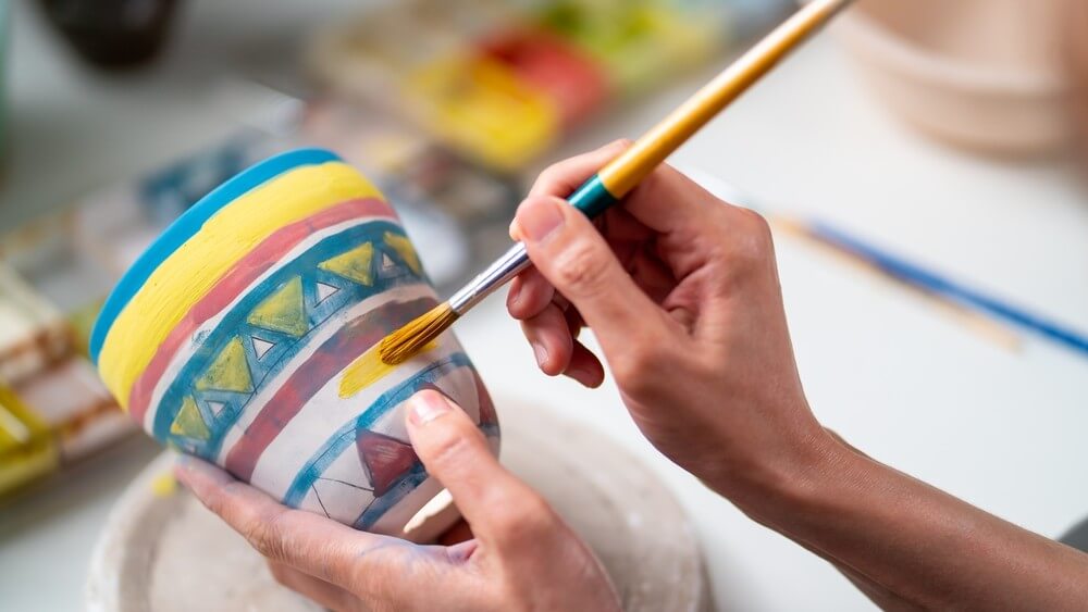 Asian woman learning color-painting of self-made pottery 