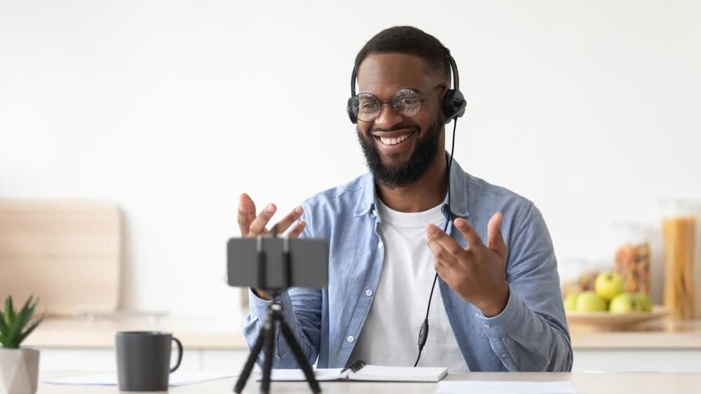 african american bearded guy teacher in glasses and headphones shooting video lesson for vlog