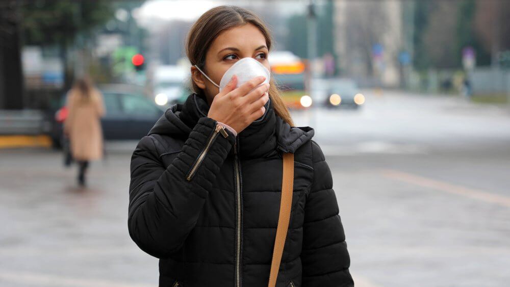 woman in a black puff jacket wearing a covid mask on the street