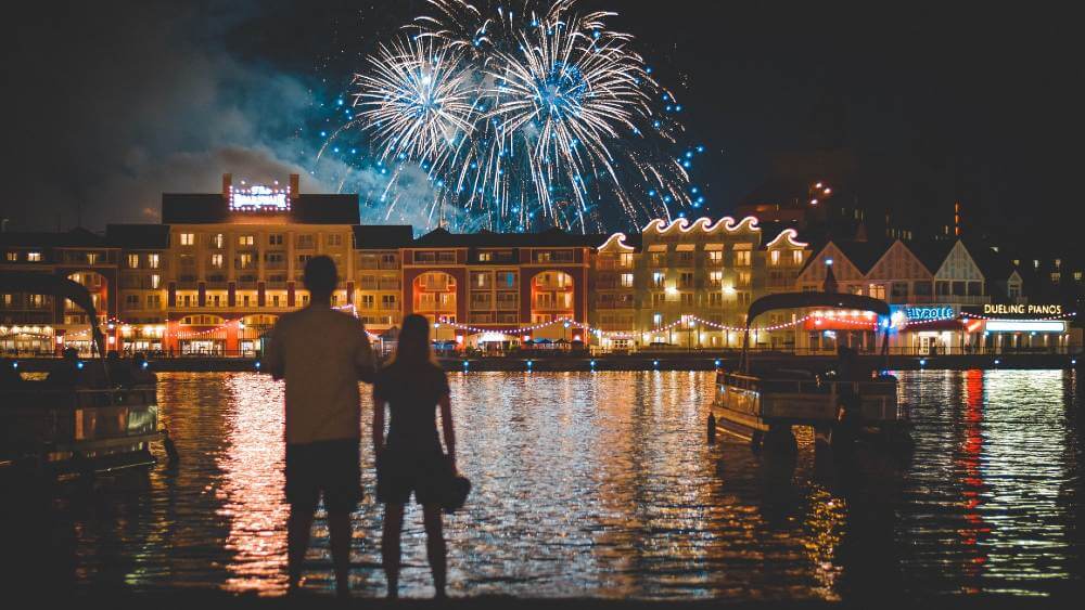 couple watching fireworks across a body of water