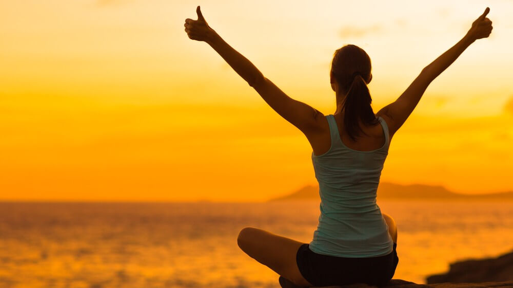 woman celebrating in the sunset during personal yoga session