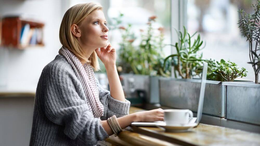 beautiful woman enjoying her alone time having coffee and looking through the window