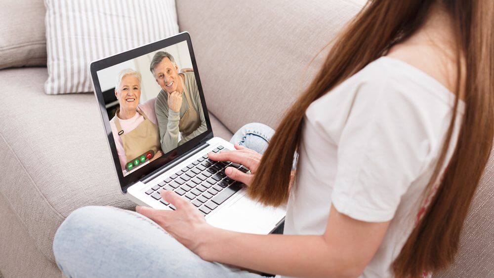 young woman video calling her parents via a laptop